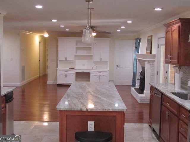 kitchen with light tile floors, a kitchen island, ceiling fan, and a fireplace