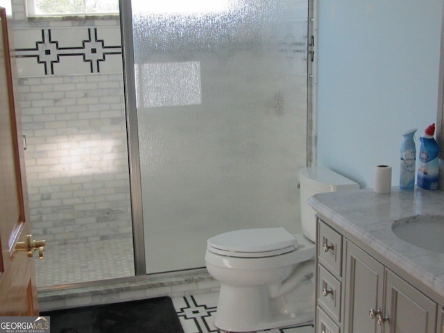 bathroom with tile floors, vanity, toilet, and a shower with door