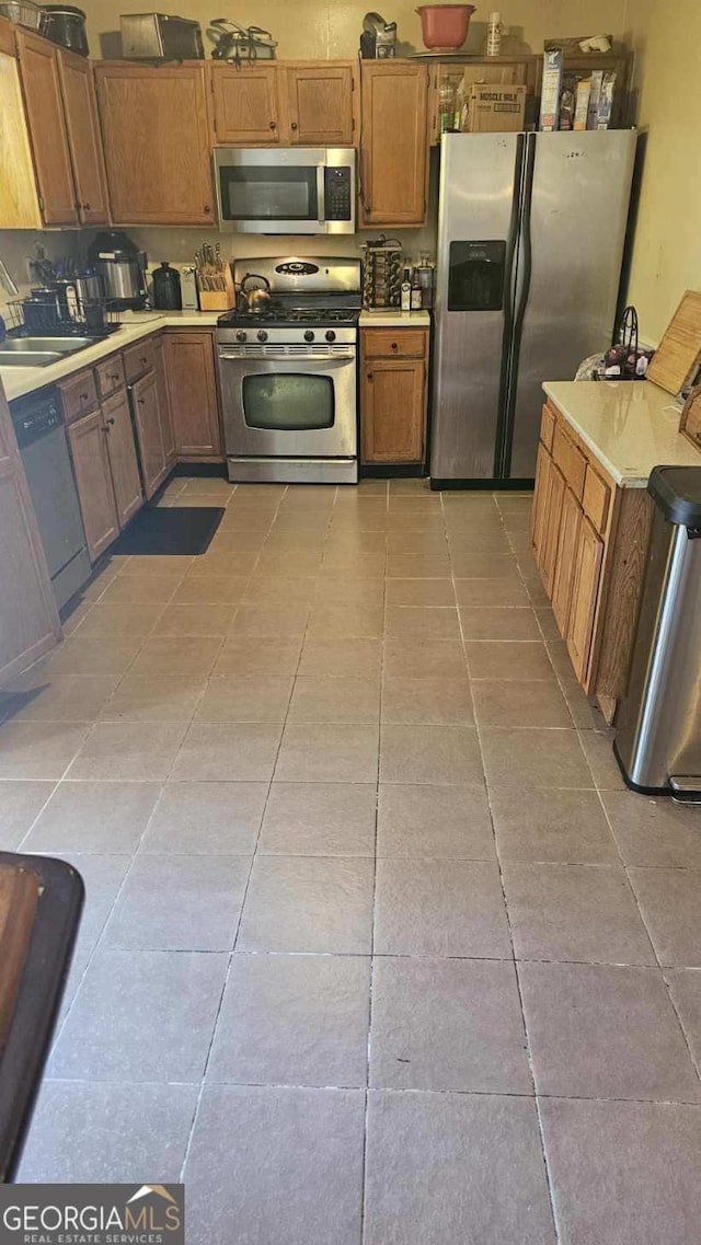 kitchen with appliances with stainless steel finishes, light tile patterned floors, and sink