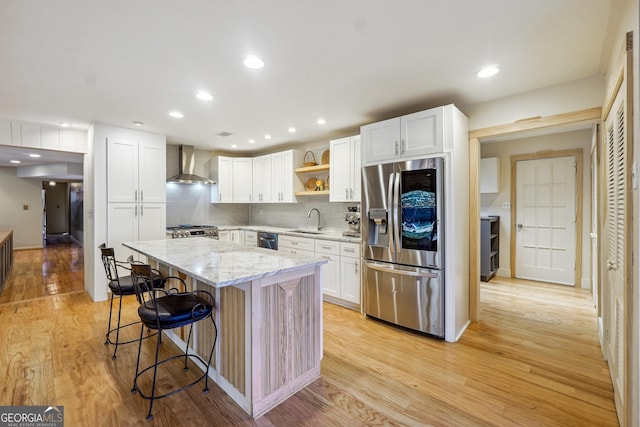 kitchen featuring sink, wall chimney range hood, stainless steel appliances, and light hardwood / wood-style flooring