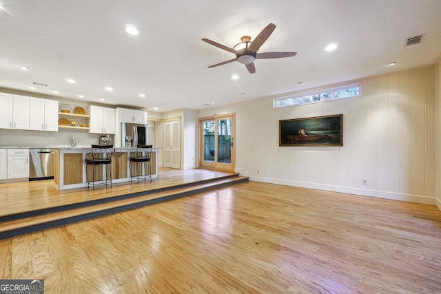 unfurnished living room featuring ceiling fan, light hardwood / wood-style floors, and sink