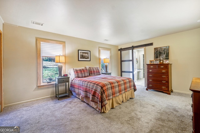 bedroom featuring carpet, a barn door, connected bathroom, and multiple windows