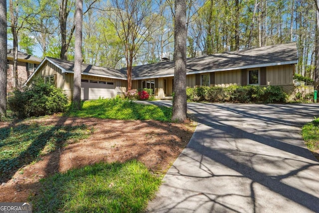 single story home with board and batten siding, a garage, and driveway