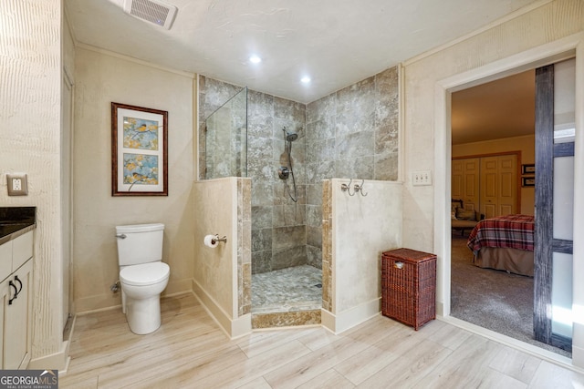 bathroom with toilet, vanity, hardwood / wood-style floors, and tiled shower