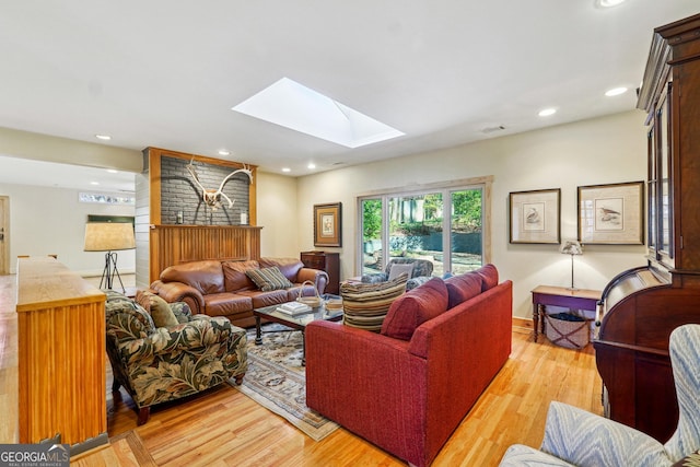 living room featuring a skylight, light hardwood / wood-style flooring, and a fireplace