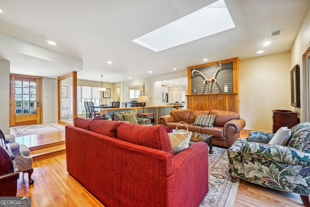 living room featuring light wood-type flooring and a skylight