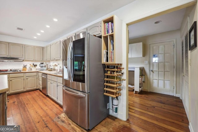 kitchen with backsplash, light wood-type flooring, and appliances with stainless steel finishes