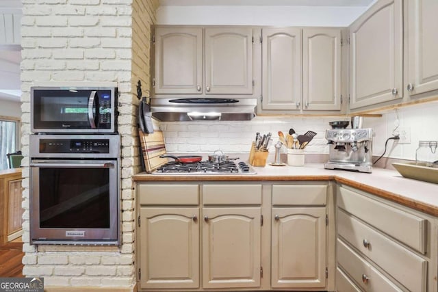 kitchen with hardwood / wood-style floors, backsplash, and appliances with stainless steel finishes