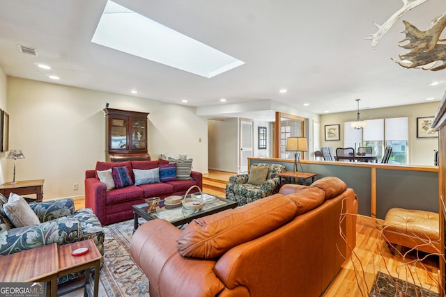 living room with light wood-type flooring and a skylight