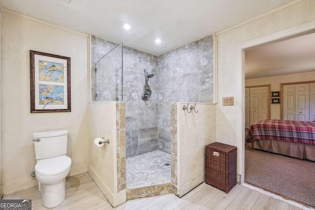 bathroom with toilet, wood-type flooring, and tiled shower