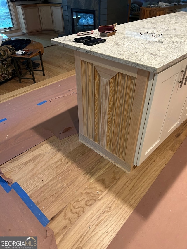 room details with light stone countertops, white cabinets, and light hardwood / wood-style flooring