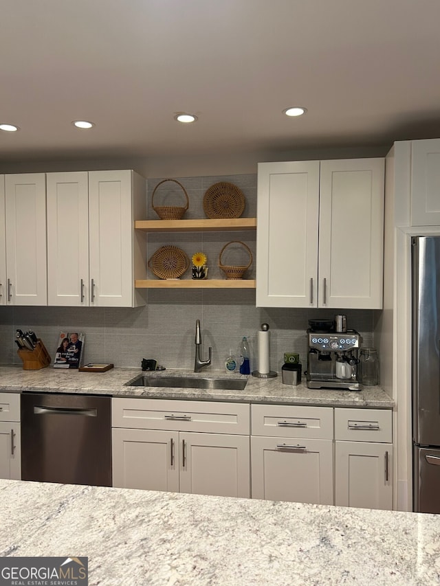 kitchen featuring decorative backsplash, white cabinetry, sink, and appliances with stainless steel finishes