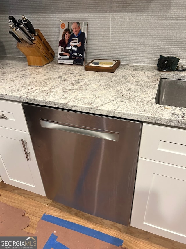 room details featuring light stone counters, white cabinets, stainless steel dishwasher, and light wood-type flooring