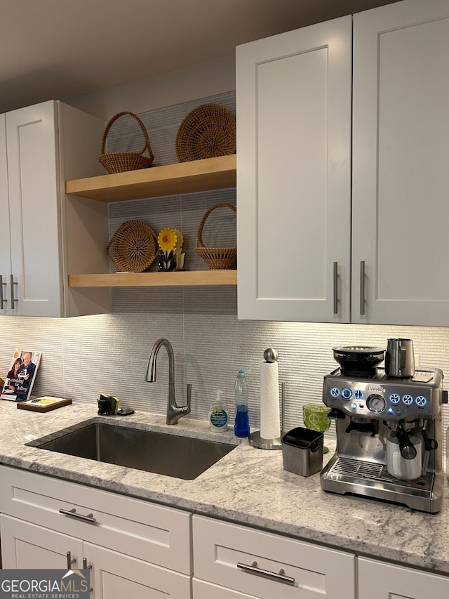 kitchen featuring light stone countertops, sink, and white cabinets