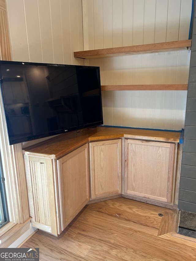 kitchen with wooden walls, light hardwood / wood-style flooring, and light brown cabinets