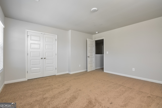 unfurnished bedroom featuring light carpet and a closet