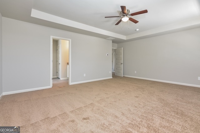 carpeted spare room with ceiling fan and a raised ceiling