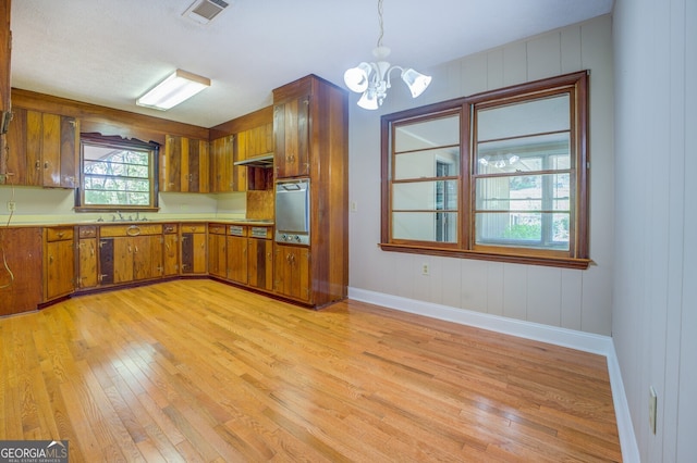 kitchen featuring hanging light fixtures, sink, light hardwood / wood-style floors, and an inviting chandelier