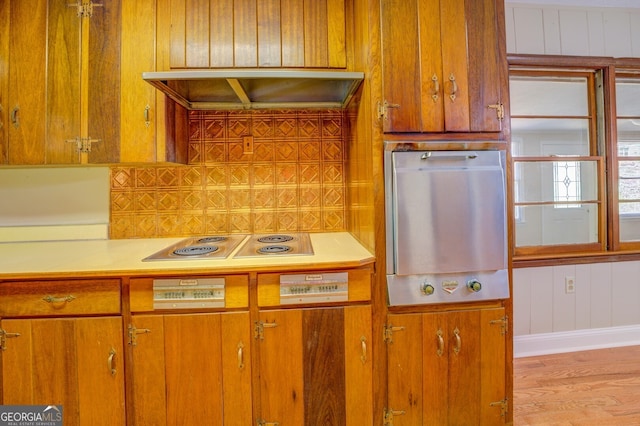 kitchen with light hardwood / wood-style flooring, wood walls, refrigerator, and range hood