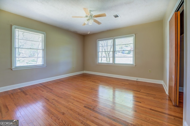 spare room with plenty of natural light, light hardwood / wood-style flooring, and ceiling fan