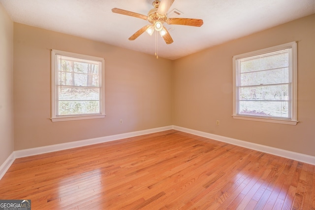 empty room with light hardwood / wood-style floors, ceiling fan, and a wealth of natural light