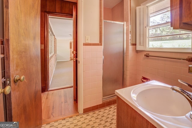 bathroom featuring wood-type flooring, plus walk in shower, and sink