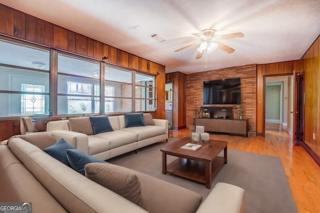 living room featuring wooden walls, light hardwood / wood-style flooring, and ceiling fan