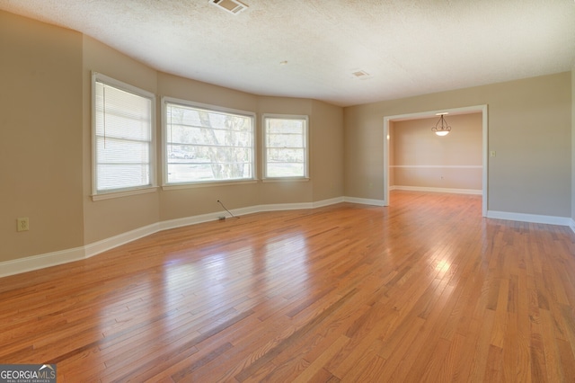 spare room featuring light wood-type flooring and a textured ceiling