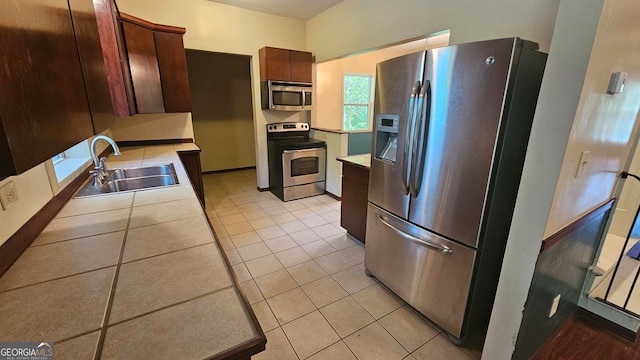 kitchen with appliances with stainless steel finishes, sink, and light tile floors