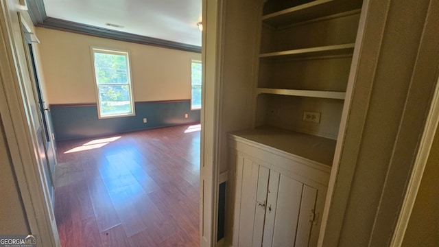 interior space featuring dark hardwood / wood-style flooring, crown molding, and built in features