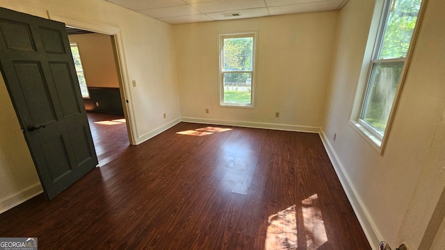 spare room featuring a drop ceiling and dark hardwood / wood-style flooring