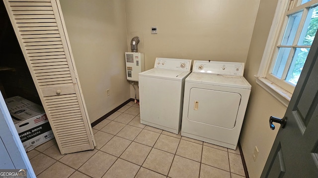 clothes washing area featuring plenty of natural light, tankless water heater, washing machine and dryer, and light tile flooring