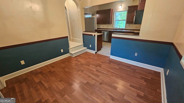 kitchen with dark brown cabinetry, sink, light hardwood / wood-style floors, and dishwasher