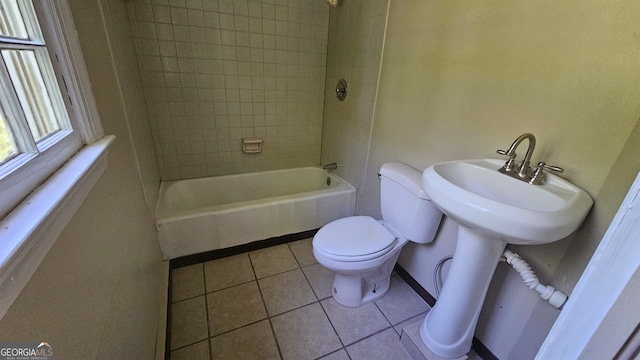 bathroom featuring tiled shower / bath combo, tile floors, and toilet