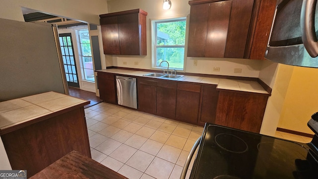 kitchen featuring dark brown cabinets, dishwasher, tile counters, and sink