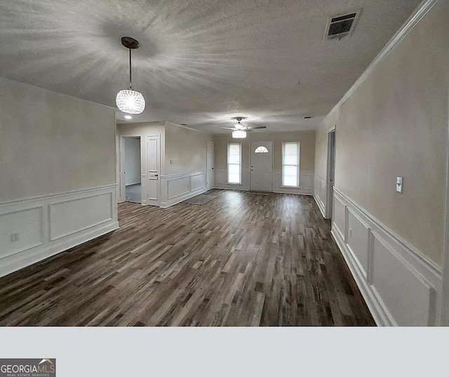 interior space featuring crown molding, a textured ceiling, dark wood-type flooring, and ceiling fan with notable chandelier