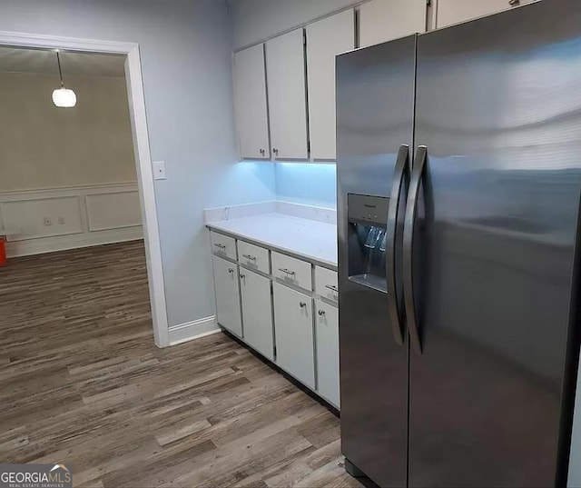 kitchen featuring stainless steel fridge, white cabinets, hardwood / wood-style floors, and decorative light fixtures