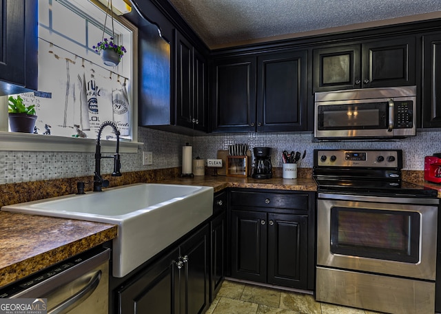 kitchen featuring appliances with stainless steel finishes, tasteful backsplash, light tile floors, a textured ceiling, and sink