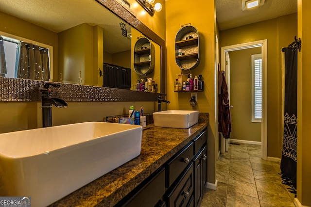 bathroom with a textured ceiling, dual sinks, tile floors, and large vanity