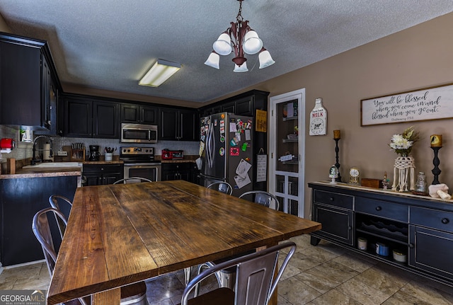 tiled dining space featuring sink, a textured ceiling, and a notable chandelier