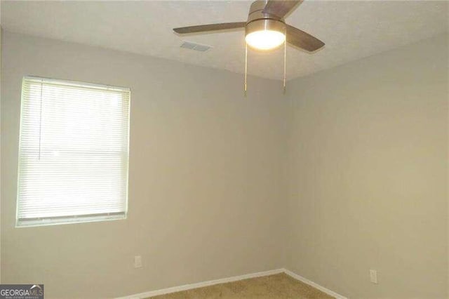 empty room featuring plenty of natural light, carpet, and ceiling fan