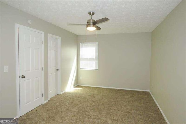 unfurnished bedroom featuring a textured ceiling, carpet floors, and ceiling fan