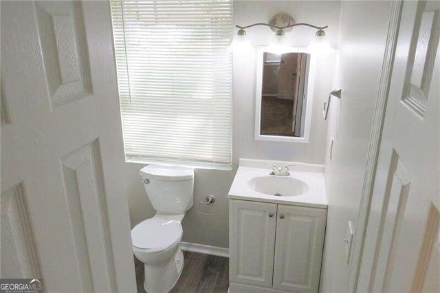 bathroom with wood-type flooring, toilet, and vanity