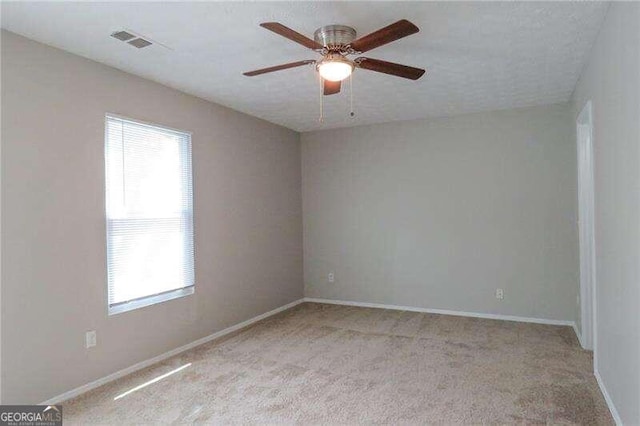 spare room featuring light colored carpet and ceiling fan