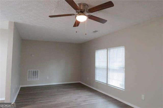 empty room featuring dark hardwood / wood-style floors, ceiling fan, and a textured ceiling