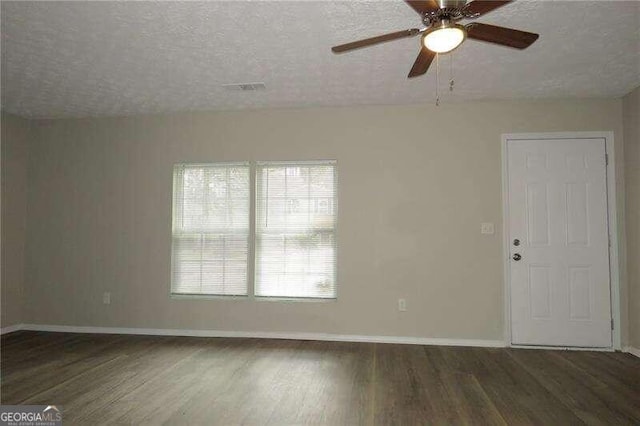 unfurnished room featuring dark hardwood / wood-style flooring, ceiling fan, and a textured ceiling