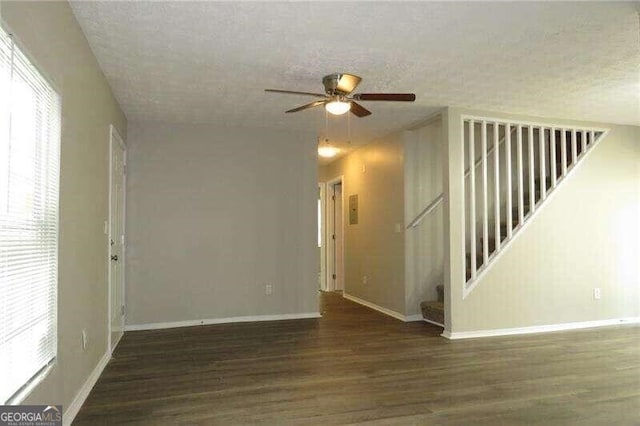 empty room featuring dark hardwood / wood-style flooring, ceiling fan, and a textured ceiling