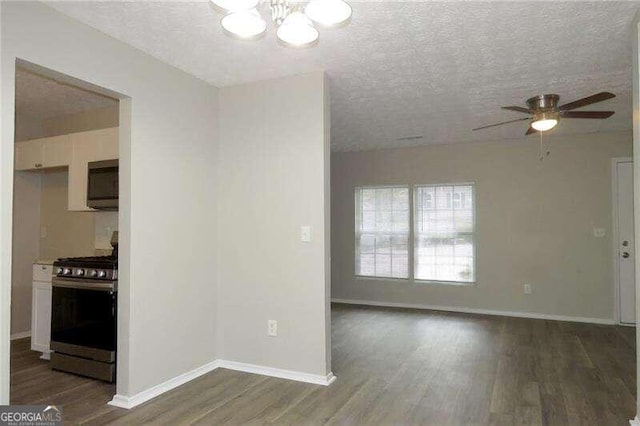 kitchen with ceiling fan with notable chandelier, appliances with stainless steel finishes, dark hardwood / wood-style flooring, and a textured ceiling