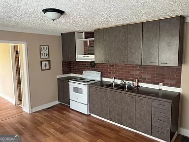 kitchen with sink, white range with electric stovetop, a textured ceiling, dark hardwood / wood-style floors, and dark brown cabinetry