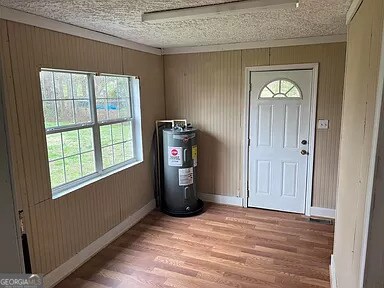 foyer entrance featuring electric water heater, a textured ceiling, and hardwood / wood-style flooring